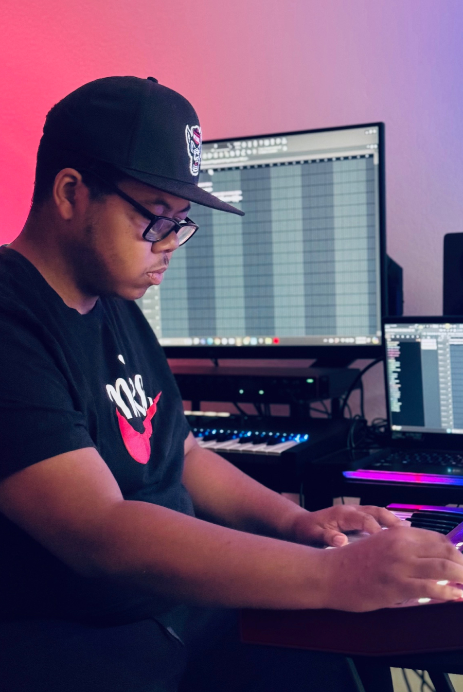 Producer playing a MIDI keyboard with FL Studio on screen